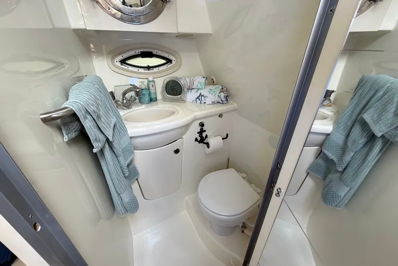 Slide: The Image of Compact bathroom in a 2008 Bayliner 300 boat, featuring sink, toilet, and towels. - 17
