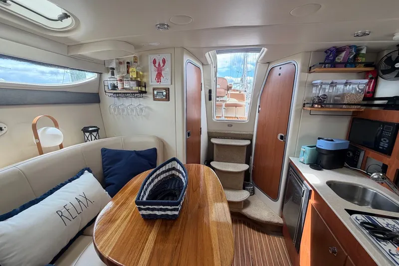 Slide: The Image of Interior of a 2008 Bayliner 300 boat with cozy seating and kitchenette. - 12