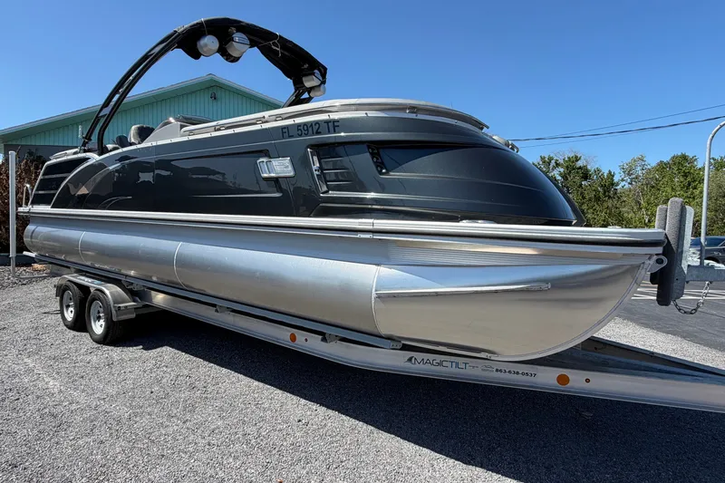 The Image of 2022 Bennington 25 QX pontoon boat on trailer, parked outdoors. - 1