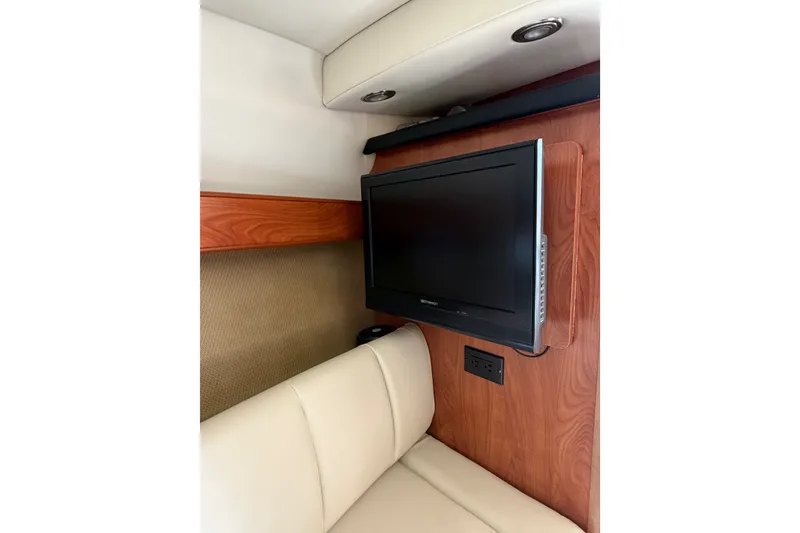 Slide: The Image of Interior of 2009 Rinker 260 Express Cruiser with mounted TV and beige seating. - 16