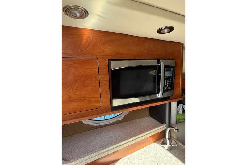 Slide: The Image of 2009 Rinker 260 Express Cruiser interior with microwave and wooden cabinetry. - 14
