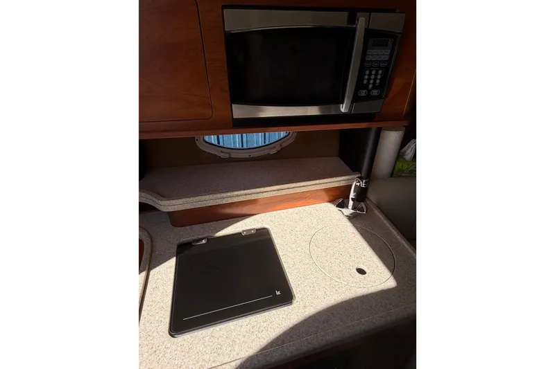 Slide: The Image of 2009 Rinker 260 Express Cruiser kitchenette with microwave and countertop. - 17
