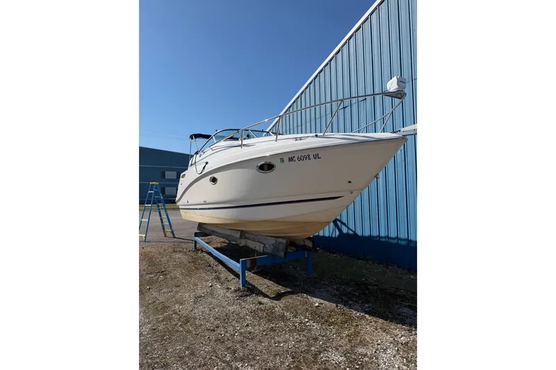 The Image of 2009 Rinker 260 Express Cruiser boat on stand beside blue building. - 1