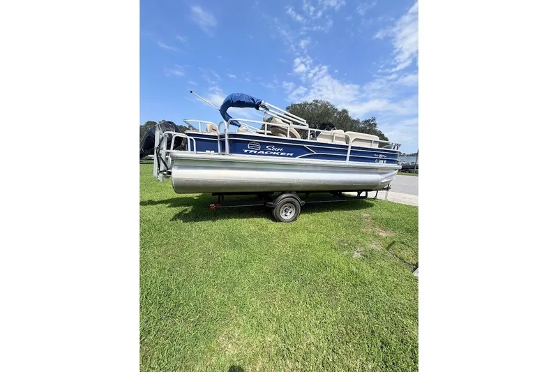The Image of 2017 Sun Tracker Fishin' Barge 20 DLX pontoon boat on grass under blue sky. - 0