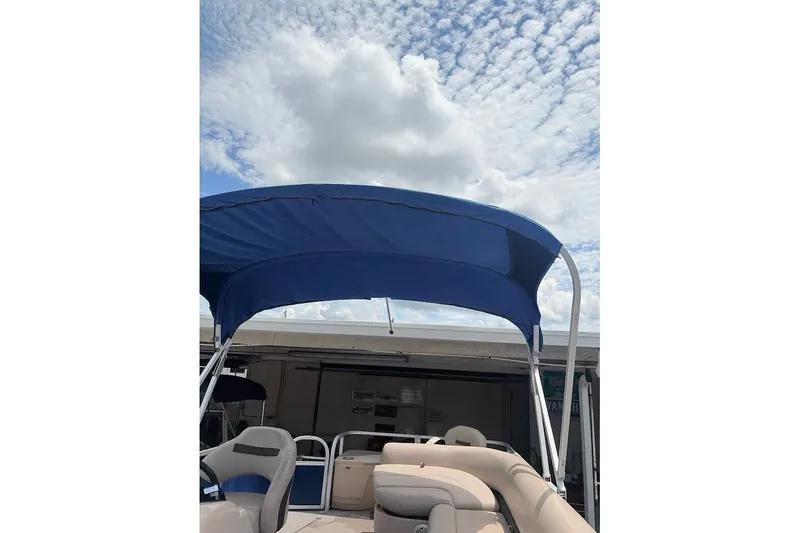 Slide: The Image of 2017 Sun Tracker Fishin' Barge 20 DLX with blue canopy under cloudy sky. - 14