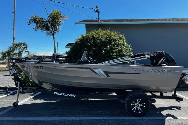 Slide: The Image of 2023 Crestliner 1600 Vision boat on trailer, parked outdoors with palm trees. - 3