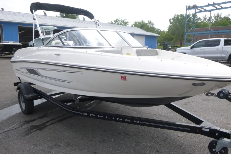 Slide: The Image of 2016 Bayliner 175 Bowrider on trailer, parked outdoors near blue building. - 3