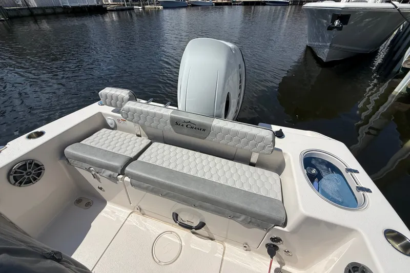 Slide: The Image of 2025 Sea Chaser 22 HFC boat interior with seating and motor, docked on calm water. - 14