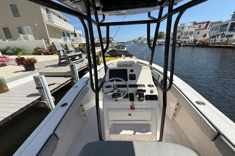 Slide: The Image of 2025 Sea Chaser 22 HFC boat docked by waterfront homes, showcasing helm and console. - 11