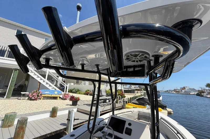 Slide: The Image of 2025 Sea Chaser 22 HFC boat with T-top and rod holders docked by waterfront homes. - 7