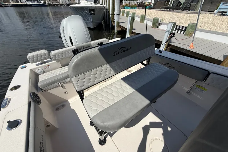 Slide: The Image of 2025 Sea Chaser 22 HFC boat interior with cushioned seating and dockside view. - 12