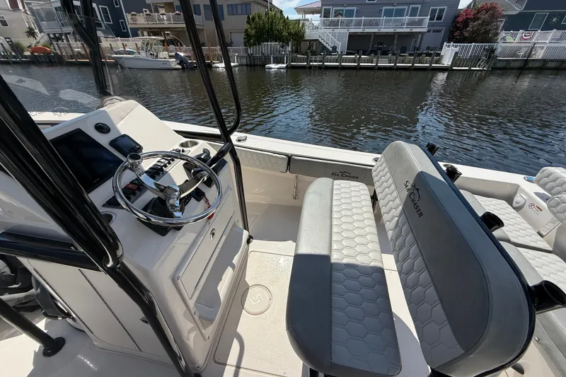 Slide: The Image of 2025 Sea Chaser 22 HFC boat interior with steering wheel and seating by the water. - 2