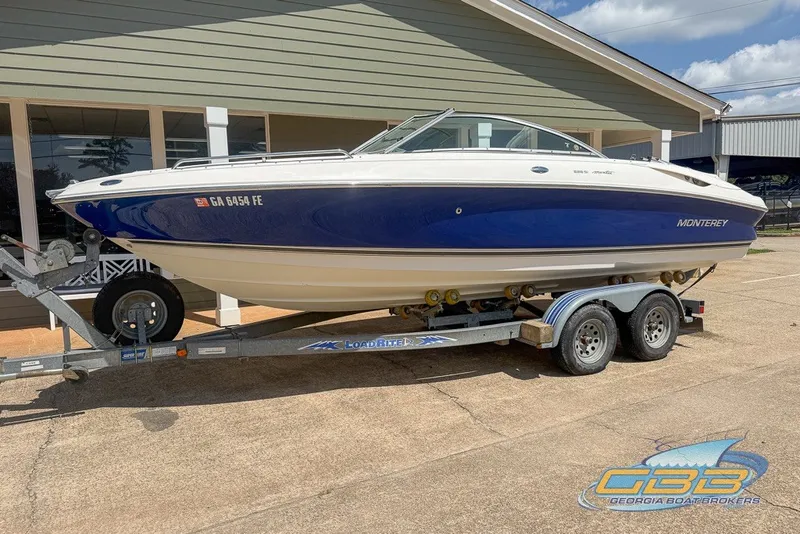 Slide: The Image of 2005 Monterey 228SI Montura Bowrider on trailer, blue and white design, parked outdoors. - 11