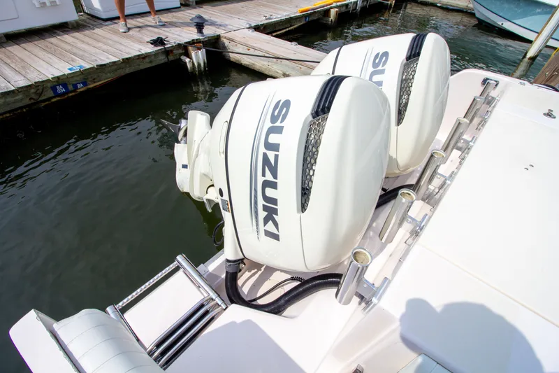 Slide: The Image of Two Suzuki outboard engines are mounted on the stern of a boat docked at a marina. - 10