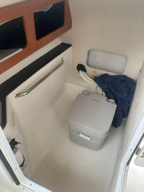 Slide: The Image of Interior of a 2010 Edgewater 245CX Crossover with a portable toilet and storage space. - 7