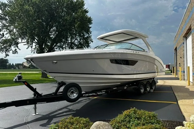 Slide: The Image of 2027 Regal 3300 boat on trailer, parked outdoors near a building. - 2