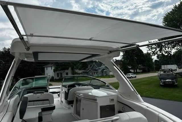 Slide: The Image of 2027 Regal 3300 boat interior with canopy, featuring seating and a kitchenette under a cloudy sky. - 37