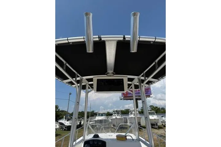 Slide: The Image of 2013 Boston Whaler 21 Montauk boat with T-top and rod holders, docked under clear sky. - 19
