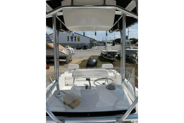 Slide: The Image of 2013 Boston Whaler 21 Montauk boat interior with steering wheel and console, parked outdoors. - 12