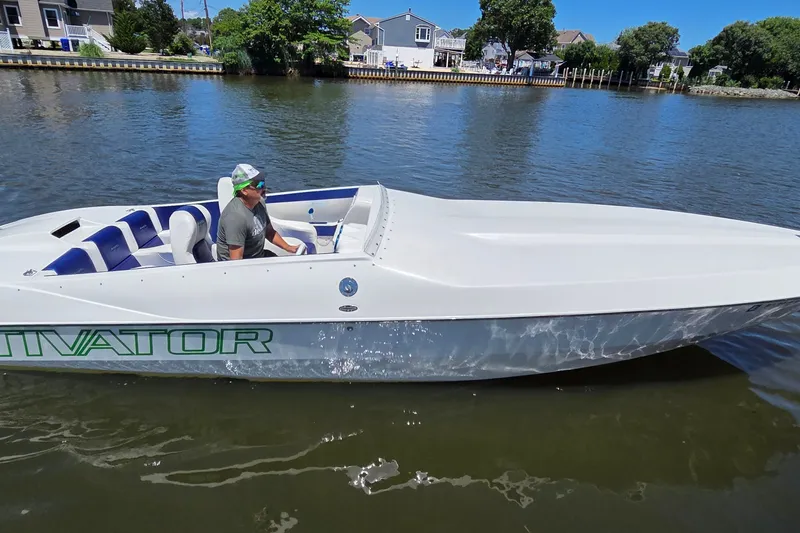 The Image of Man driving 2021 Activator 30 speedboat on a calm river near residential area. - 1