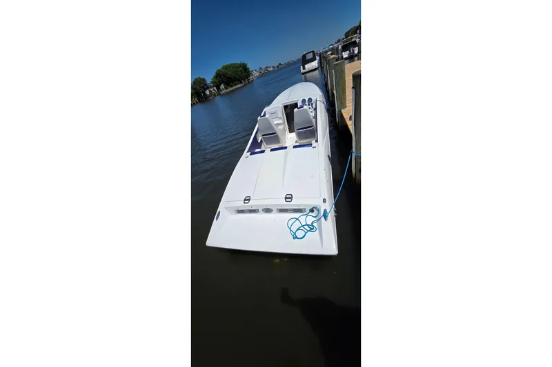 Slide: The Image of 2021 Activator 30 boat docked on calm water with clear blue sky. - 16