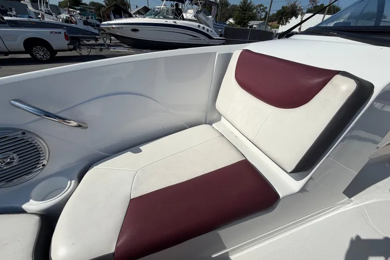 Slide: The Image of 2019 Tahoe 550 TS boat seat with maroon and white upholstery, docked near other boats. - 38