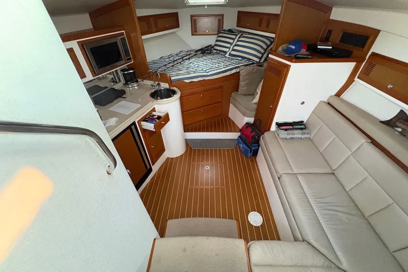 Slide: The Image of 2002 Cabo 31 Express cabin interior with kitchenette, bed, and seating area. - 11
