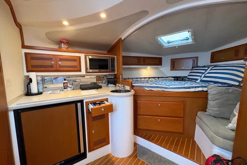 Slide: The Image of 2002 Cabo 31 Express cabin interior with kitchenette, bed, and seating area. - 13