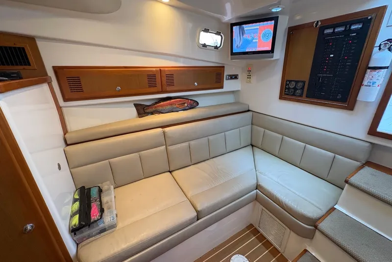 Slide: The Image of Interior of 2002 Cabo 31 Express boat with beige seating and mounted TV. - 12