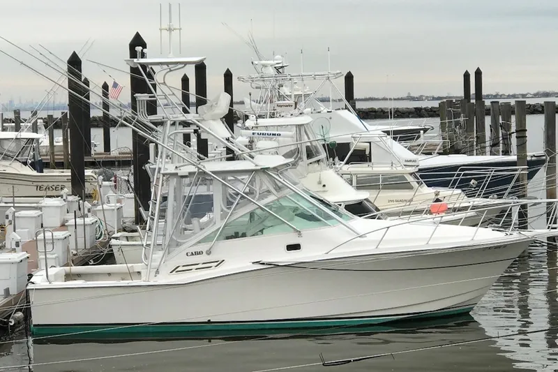 Slide: The Image of 2002 Cabo 31 Express boat docked in a marina with other vessels. - 0