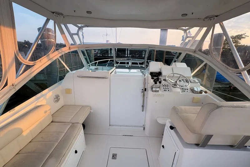 Slide: The Image of 2002 Cabo 31 Express boat interior with helm, seating, and controls at sunset. - 7