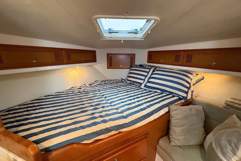 Slide: The Image of Cozy cabin interior of 2002 Cabo 31 Express with striped bedding and wooden storage. - 14