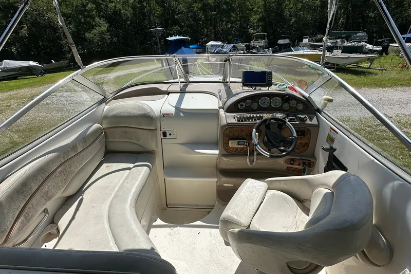 Slide: The Image of 2006 Larson Cabrio 240 boat interior with steering wheel and seating, parked outdoors. - 17