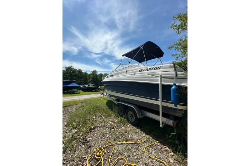 Slide: The Image of 2006 Larson Cabrio 240 boat on trailer under clear blue sky. - 2