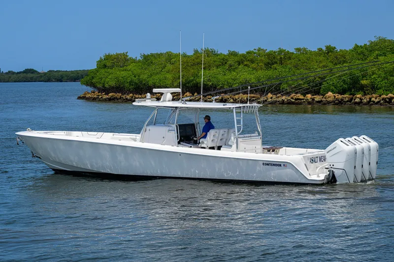 Slide: The Image of 2023 Contender 44 ST boat cruising on a calm waterway with lush greenery. - 5