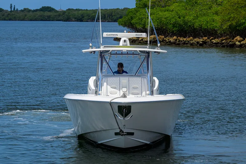 Slide: The Image of 2023 Contender 44 ST boat cruising on a calm waterway with lush greenery. - 2