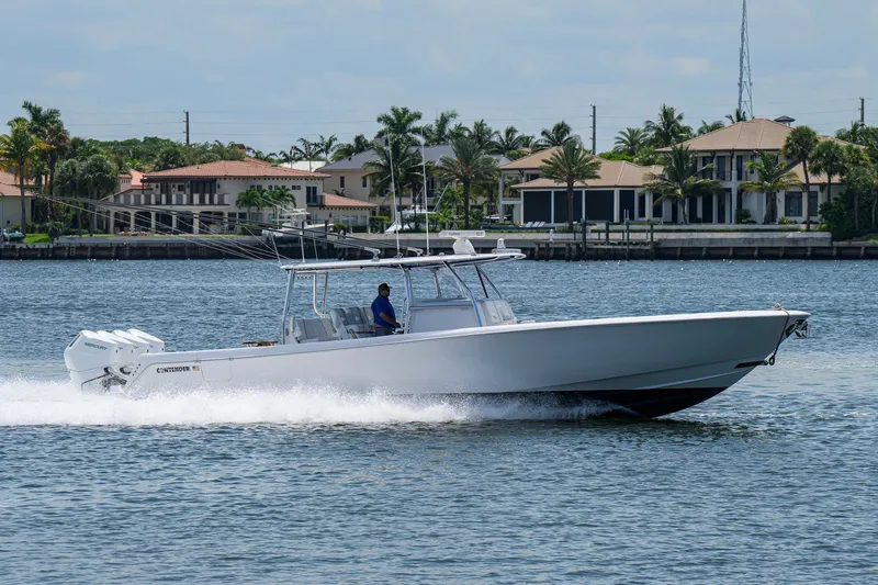 Slide: The Image of 2023 Contender 44 ST boat cruising on water near luxury waterfront homes. - 8