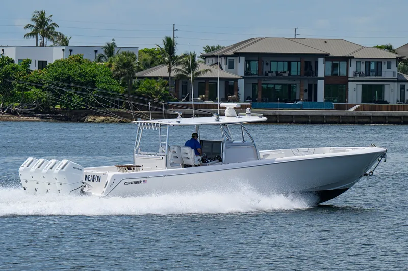 Slide: The Image of 2023 Contender 44 ST boat cruising on water near luxury waterfront homes. - 9