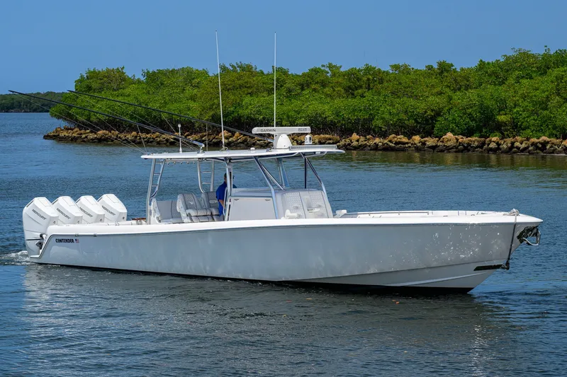 Slide: The Image of 2023 Contender 44 ST boat cruising on a calm waterway with lush greenery. - 1