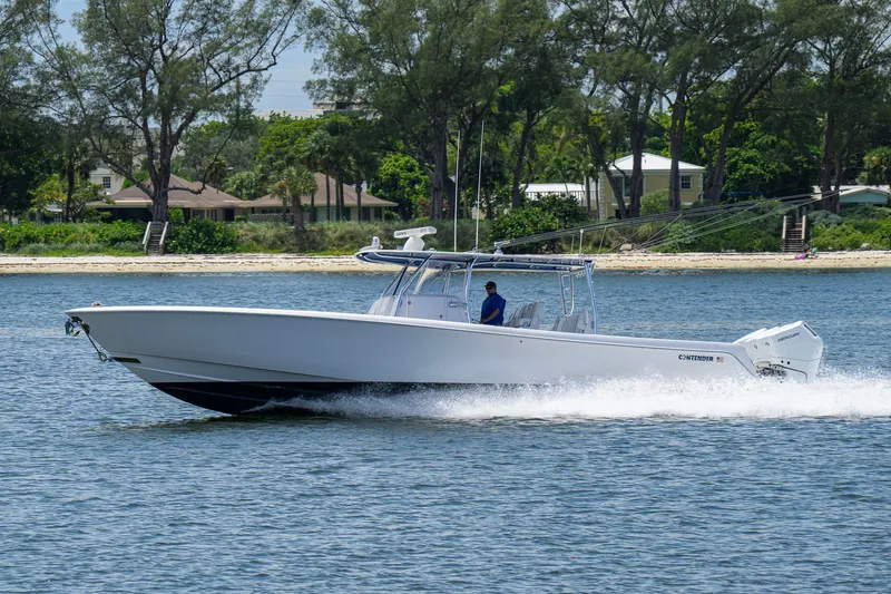Slide: The Image of 2023 Contender 44 ST boat cruising on water near a tree-lined shore. - 10