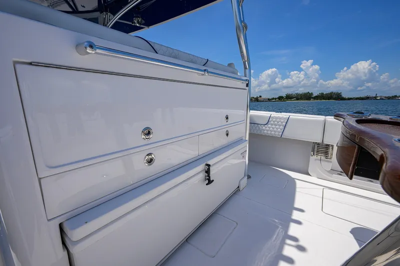 Slide: The Image of 2023 Contender 44 ST boat interior with storage drawers, overlooking serene water and blue sky. - 48
