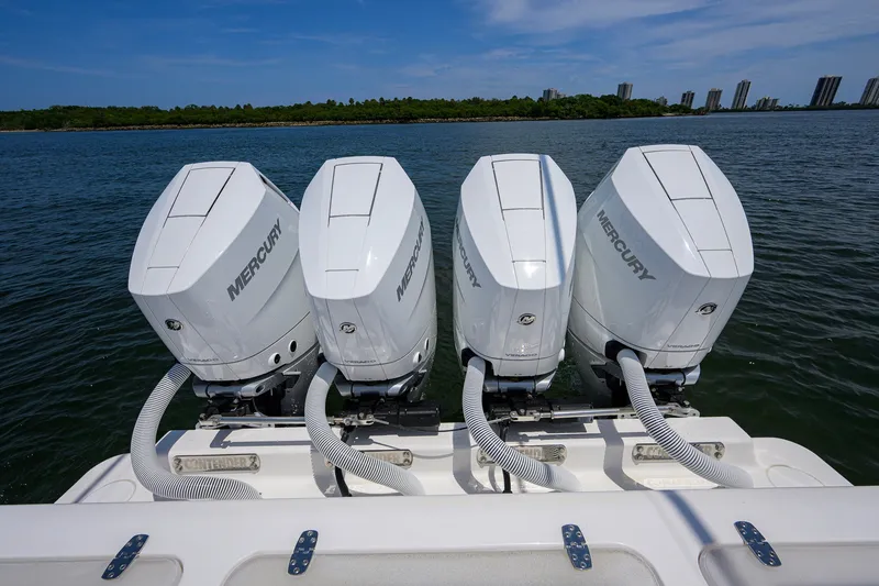 Slide: The Image of Four Mercury outboard engines on a 2023 Contender 44 ST boat, docked on calm water. - 52