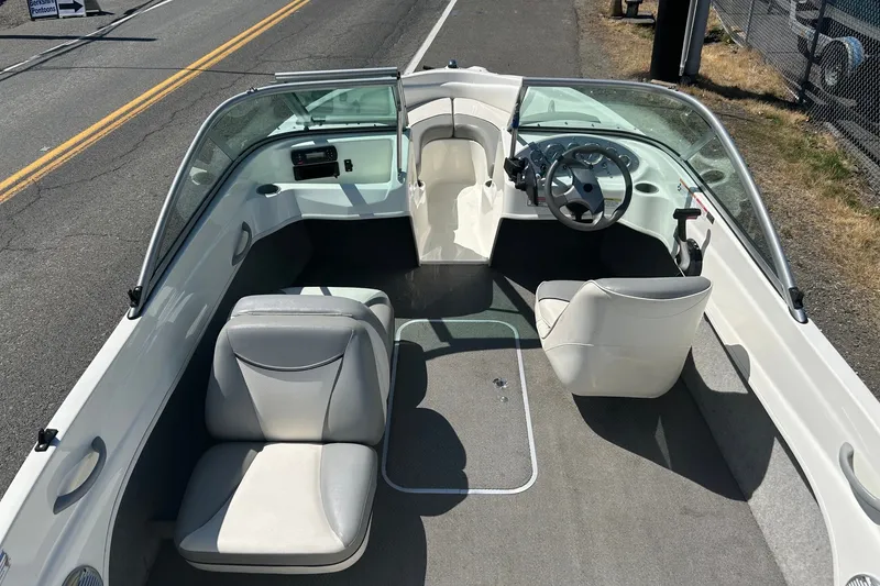 Slide: The Image of 2011 Bayliner 175 Bowrider interior with seating and steering wheel, parked on roadside. - 7