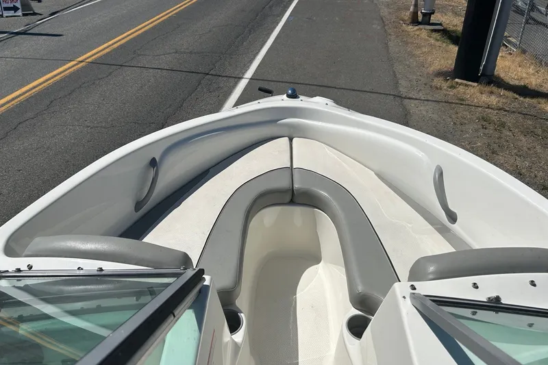 Slide: The Image of 2011 Bayliner 175 Bowrider boat interior with gray seating, parked on roadside. - 6