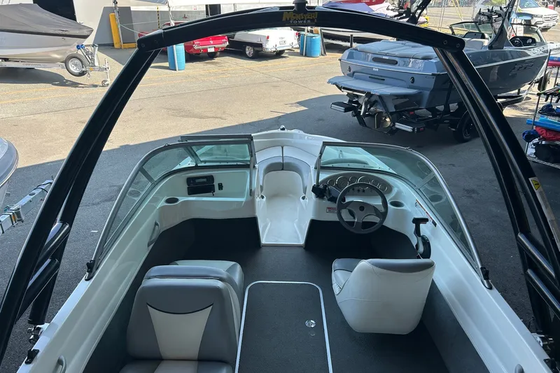 Slide: The Image of 2011 Bayliner 175 Bowrider interior with steering wheel and seating, parked in a marina. - 2