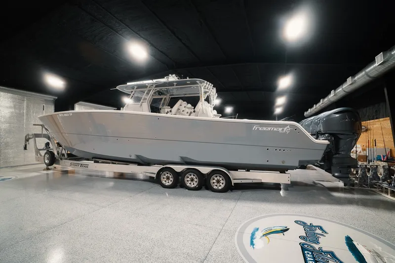 Slide: The Image of 2023 Freeman 42LR boat on trailer in a well-lit indoor showroom. - 25