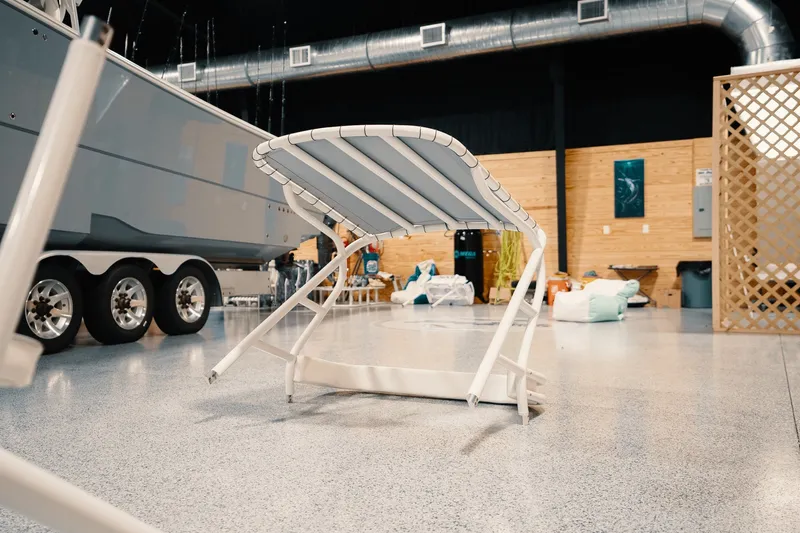 Slide: The Image of Indoor boat showroom featuring a 2023 Freeman 42LR with a white lounge chair. - 94