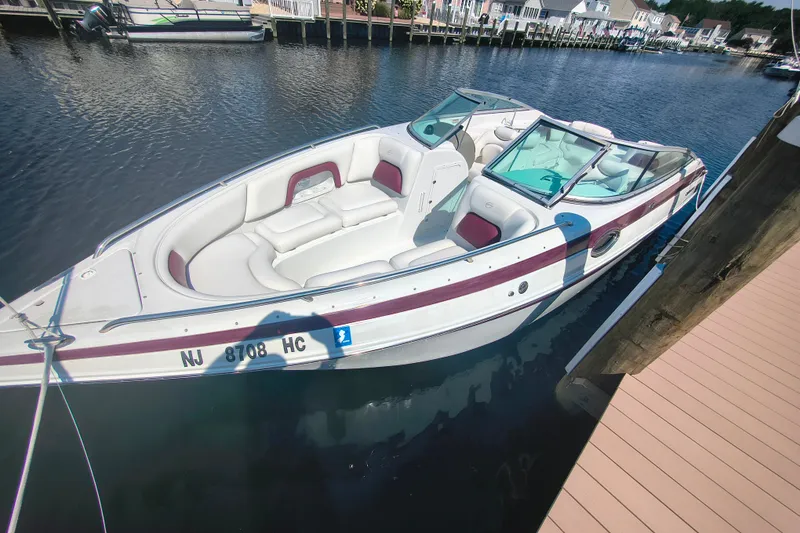 Slide: The Image of 2004 Crownline 270 BR boat docked in a marina, featuring white and maroon seating. - 18