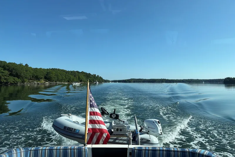 Slide: The Image of 2019 Back Cove 41 cruising on a serene lake with American flag and inflatable boat. - 2