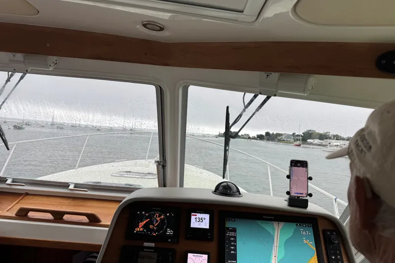 Slide: The Image of Interior view from a 2019 Back Cove 41 boat, showing navigation equipment and rainy weather. - 6